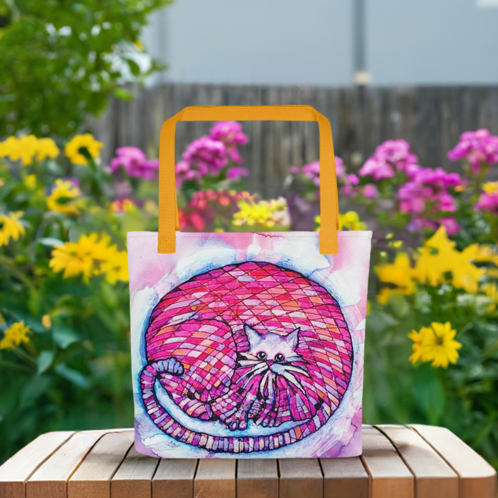 Big Pink Cat Tote Bag with colorful cat artwork and orange handles in outdoor garden setting