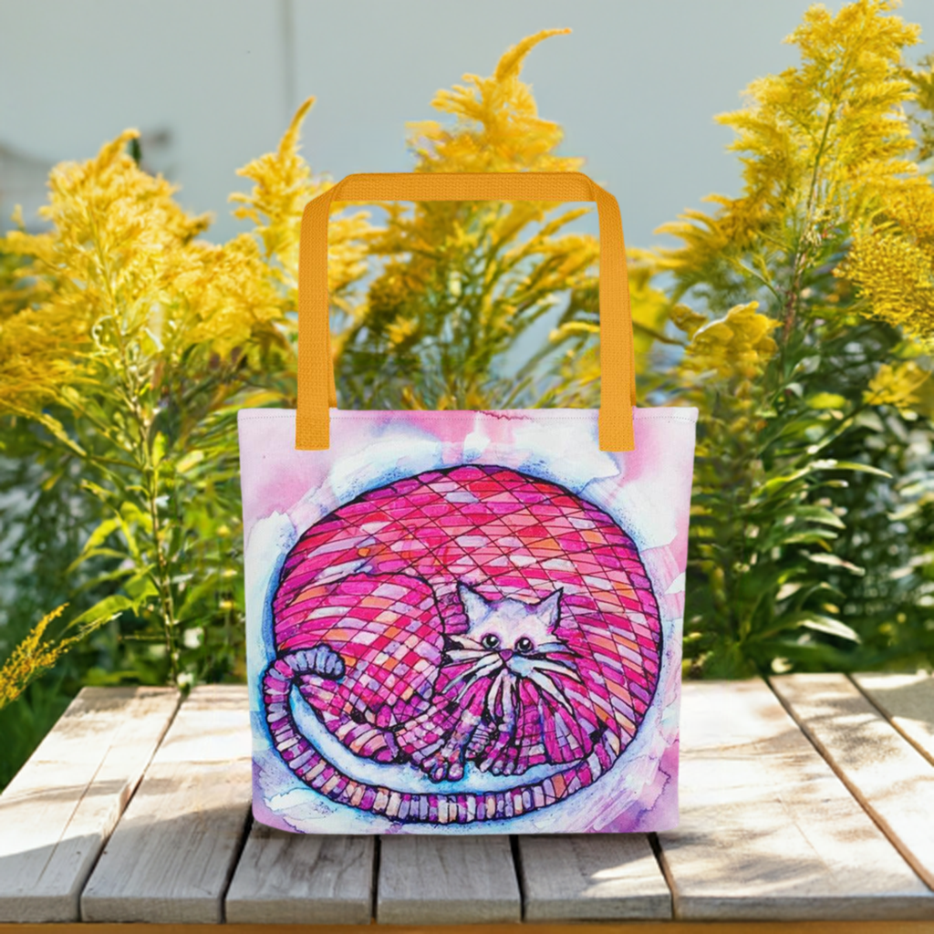 Big Pink Cat Tote Bag with colorful cat artwork and yellow handles on wooden table outdoors