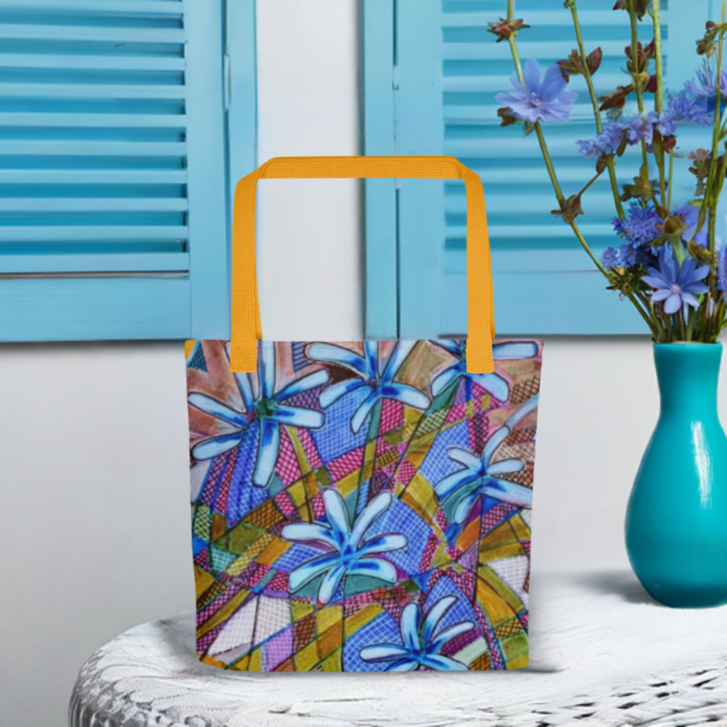 Blue Chicory Abstract Tote bag with colorful floral design and orange handles on a white table with blue shutters background