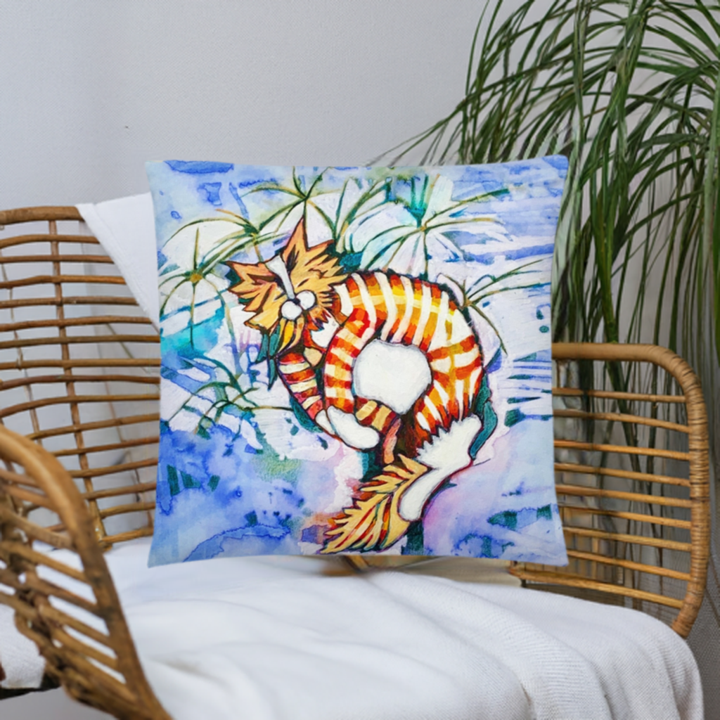 Orange tabby cat pillow with artistic design by Joy Calonico on wicker chair with plant background