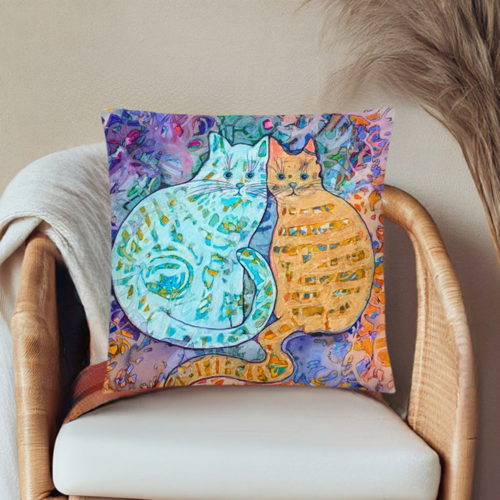 Cat Friends Pillow with colorful artistic cat design on a wicker chair