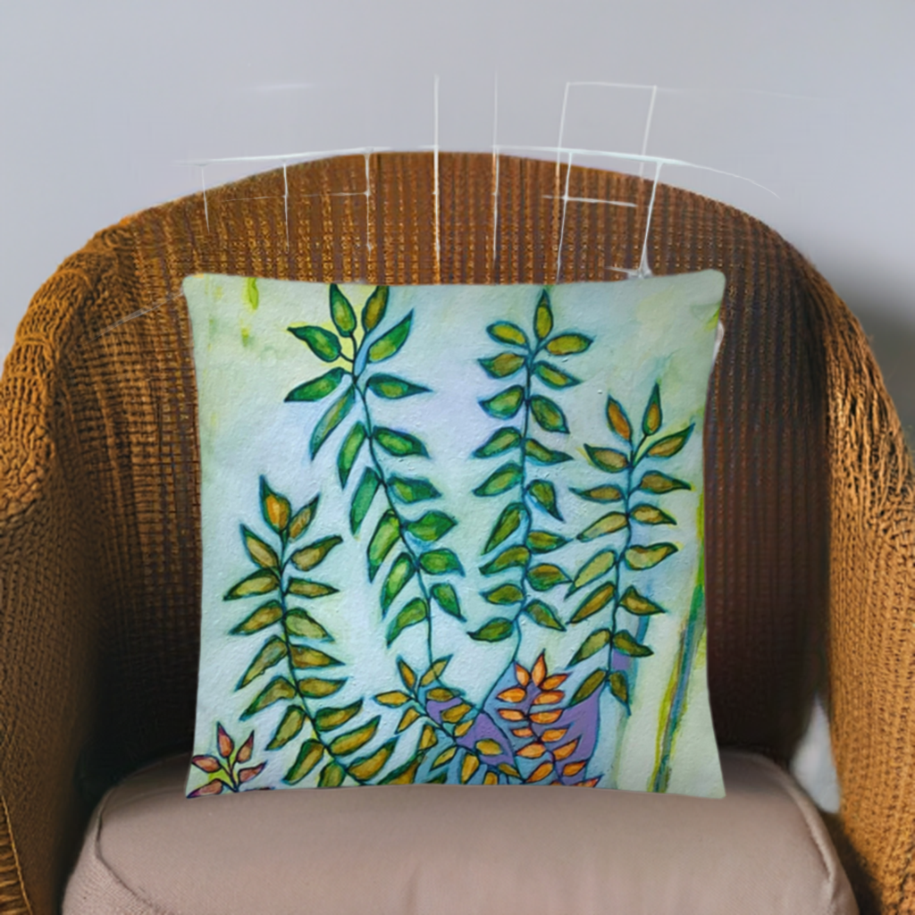 Green Leaves Pillow with vibrant leaf artwork by Joy Calonico on a wicker chair