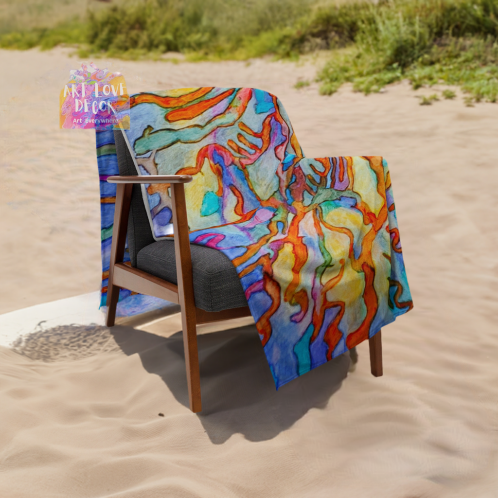 Colorful coral reef abstract throw blanket with soft silk touch fabric draped over a wooden chair on the beach