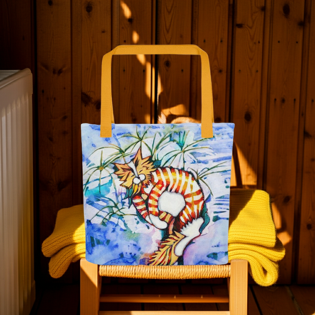 Orange tabby cat tote bag with vibrant artwork and yellow handles on wooden chair